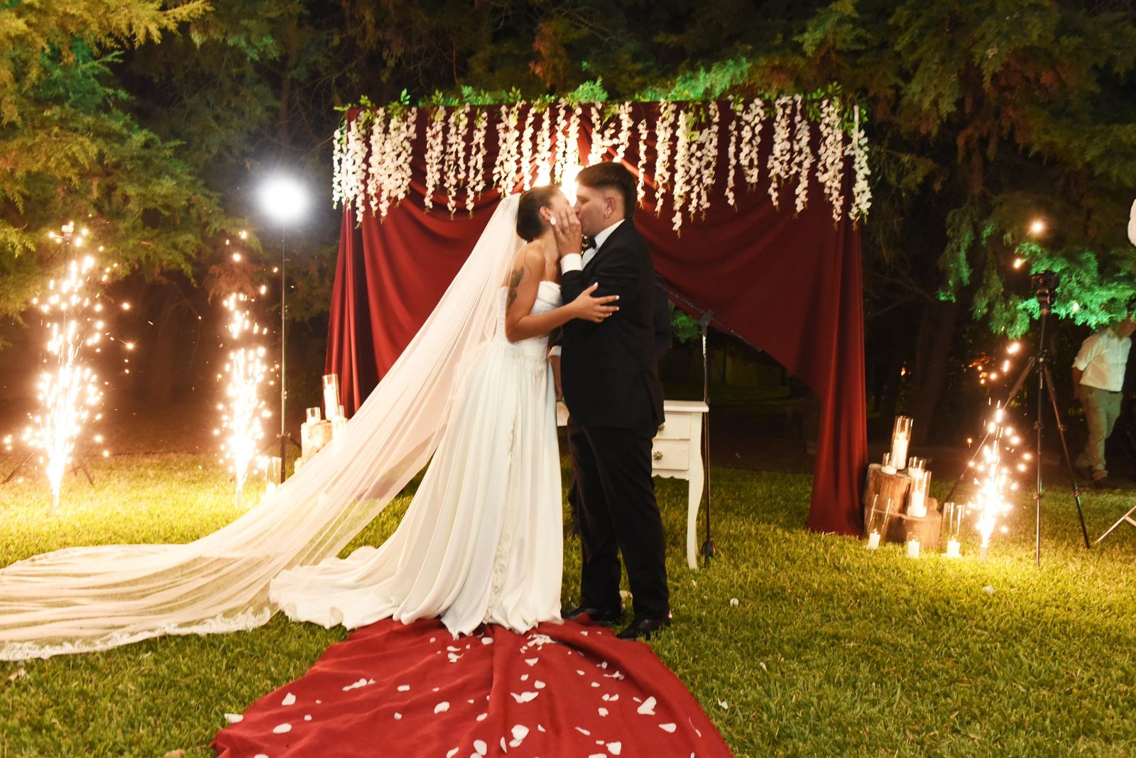 Novios besándose con chispas frías de fondo en ceremonia al aire libre